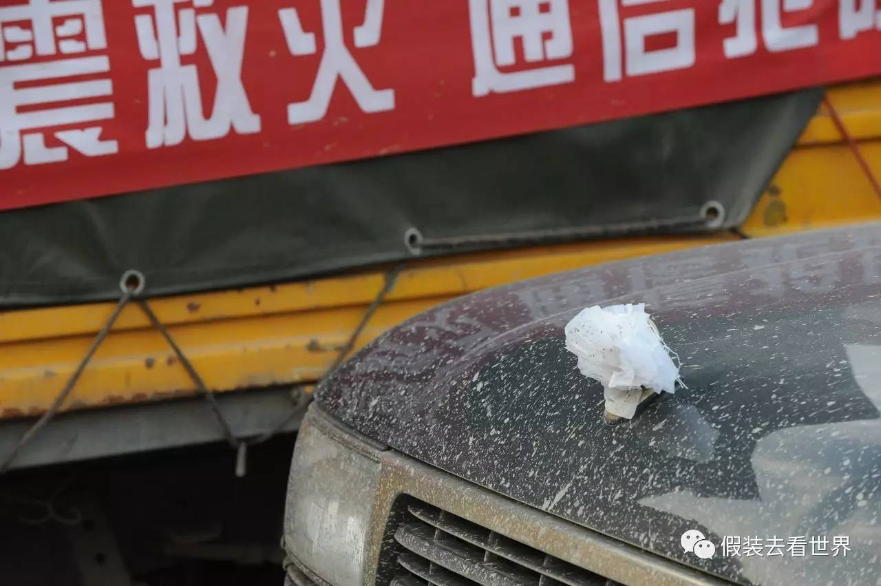 当时车上车主都挂着小白花震中映秀,几个灾民捂着鼻子经过一块空地