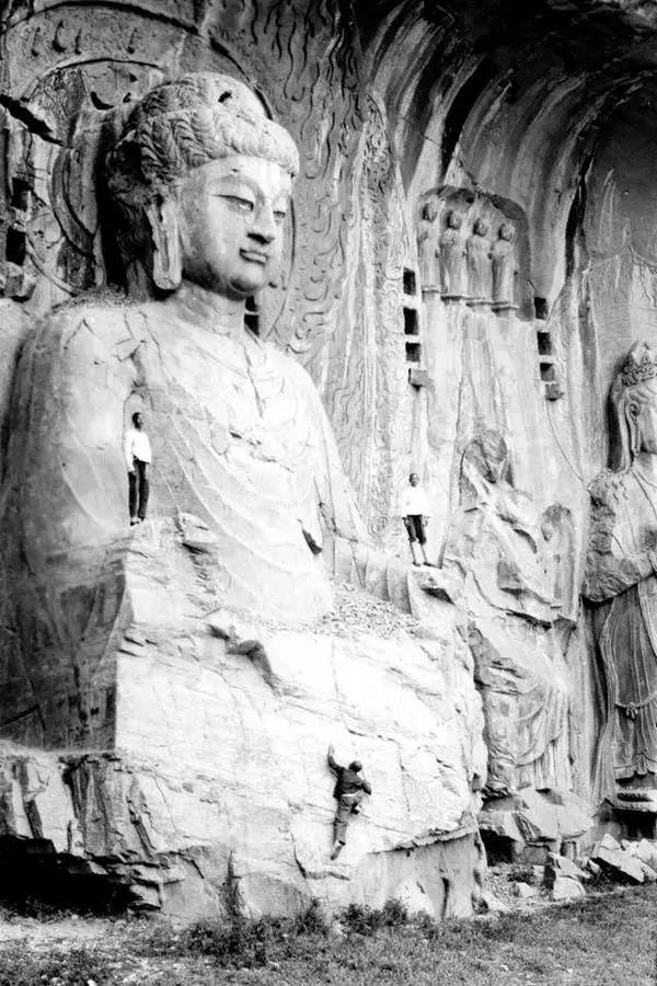 河南洛阳龙门石窟,雕像上的游人;中国,1938年.