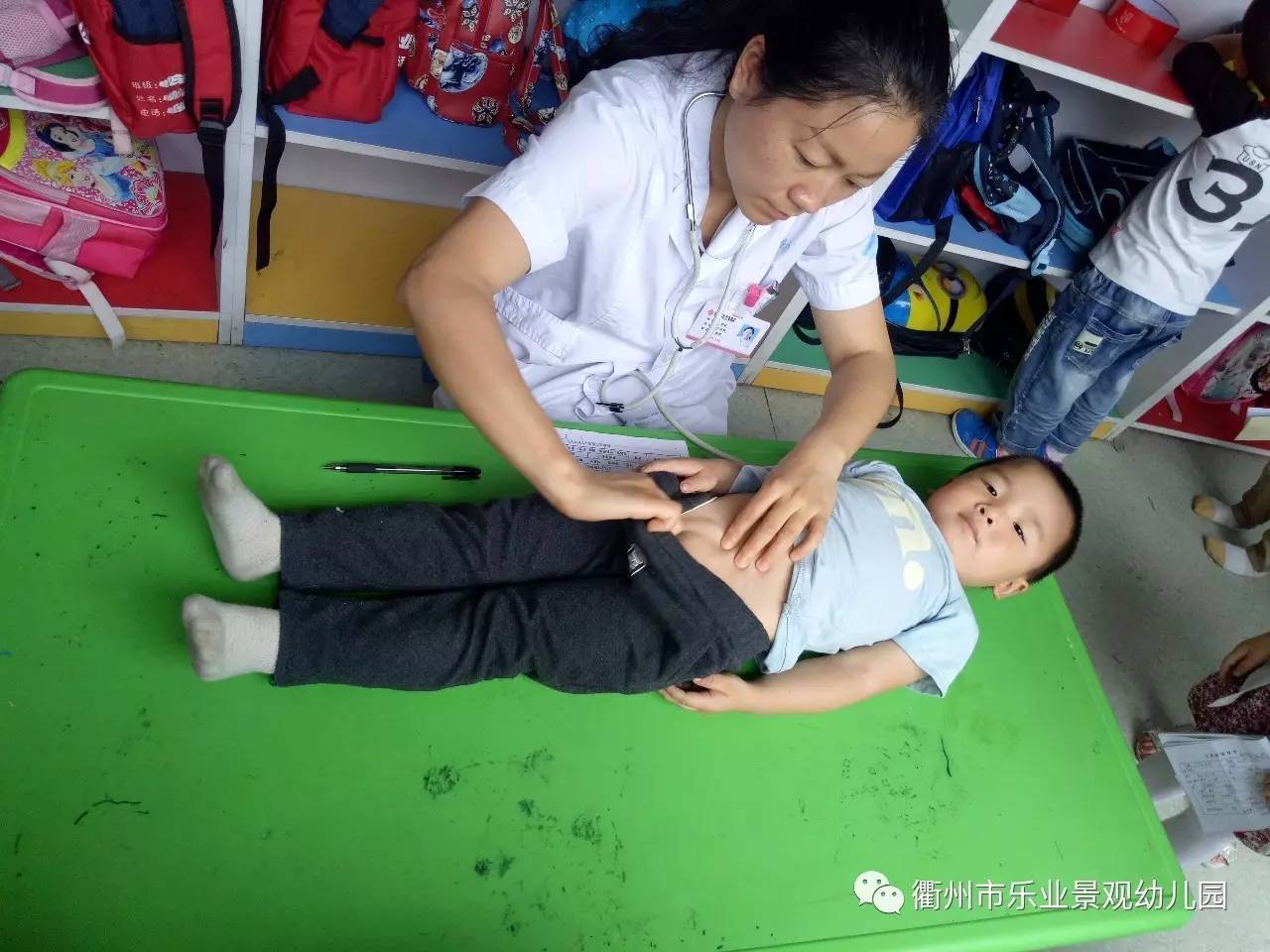 医生正在为孩子做身体检查,瞧小家伙多听话呀,躺着医生面前.