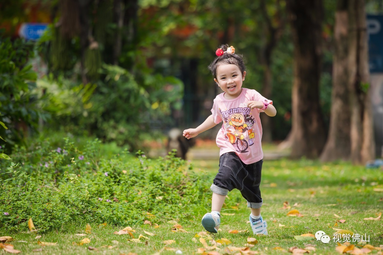 禅城区岭南明珠体育馆门前的草坪上,一位小朋友正在奔跑.