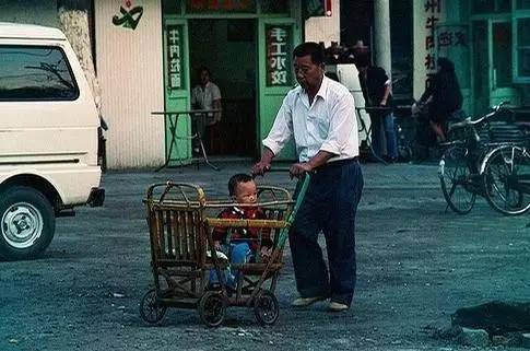 1996年中国历史老照片:爷爷推着小孙子出去逛街,小家伙很好奇.