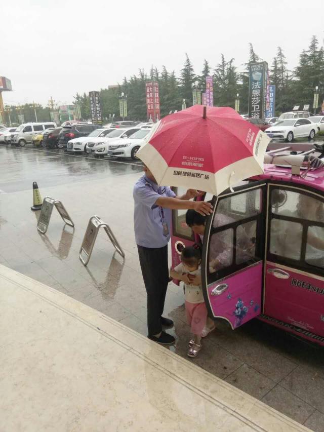 一位客户拎着包冒雨走来,离她最近的保安急忙撑伞跑过去,接她走进商场