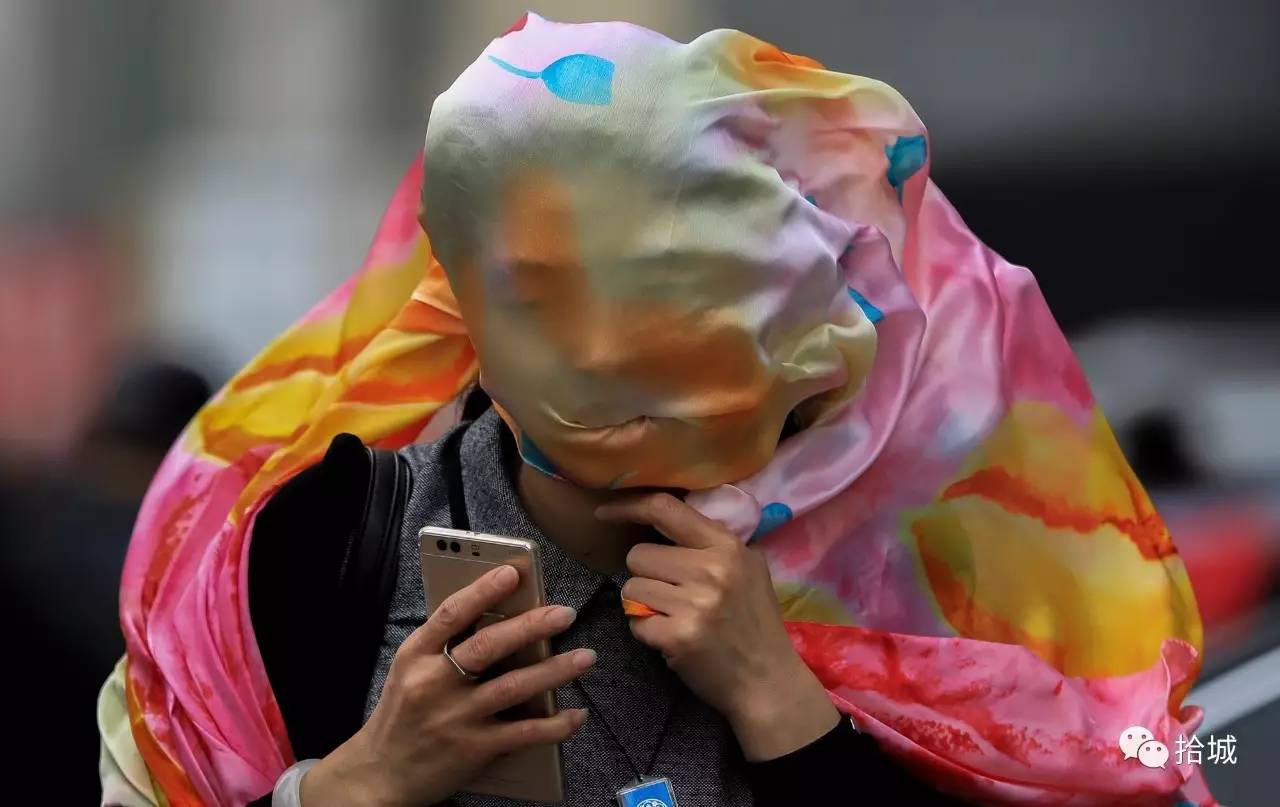 沈阳 2017年5月6日,一名用纱巾将头部包裹起来的女士在大风扬沙天气